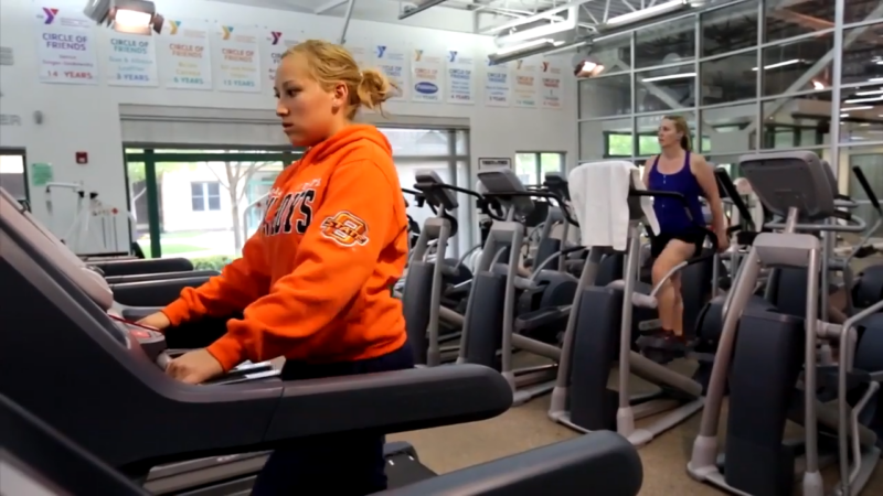 Two Women Exercising Indoors on Cardio Machines