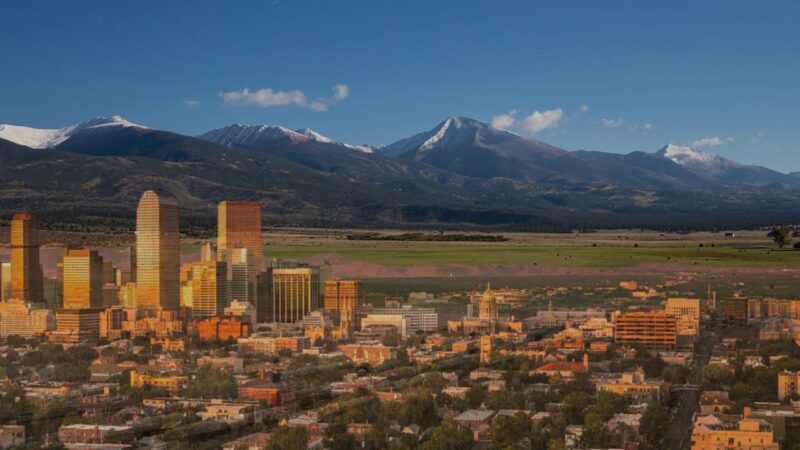 A Composite Image Illustrating the Contrast Between Colorado's Urban Areas, Represented by The Skyscrapers of A City Skyline, and Its Rural Landscapes, Depicted by Expansive Fields and Mountainous Backdrops