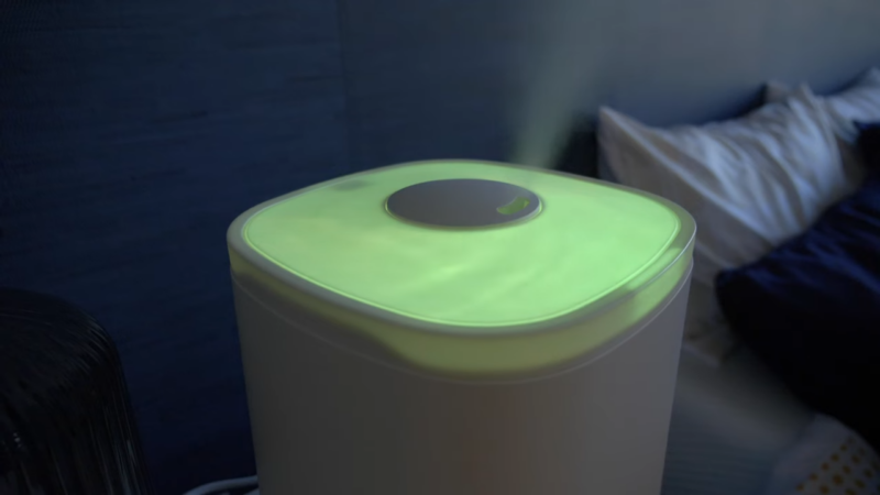 A Running Humidifier Emitting a Green Glow and Vapor in A Bedroom Setting