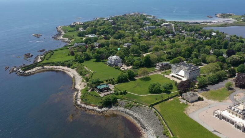 An Aerial View of A Scenic Coastal Area in Rhode Island, Featuring Large Historic Mansions Surrounded by Lush Greenery, with A Rocky Shoreline and The Ocean in The Background