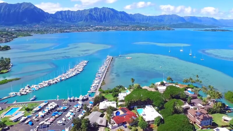 Aerial View of A Vibrant Marina in Hawaii Showcasing Boats, Surrounding Waters, and A Mountainous Backdrop