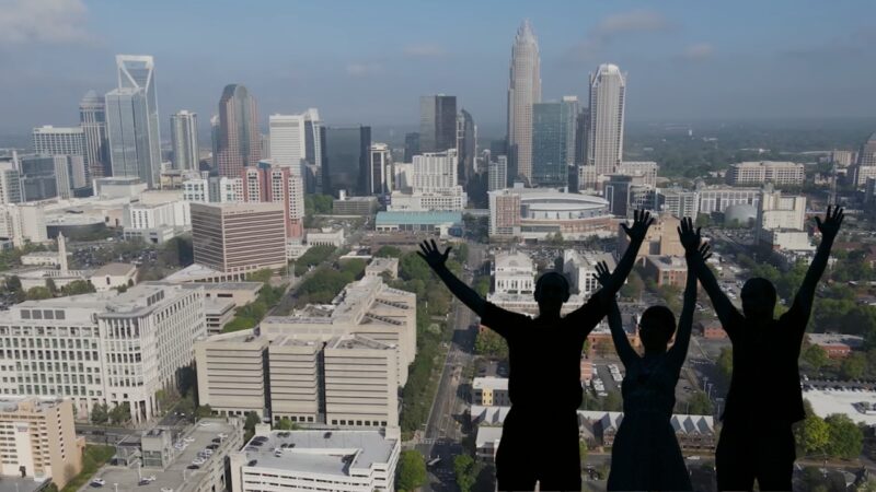 The Image Depicts Three Silhouettes of People with Their Arms Raised in Celebration Against the Backdrop of The Charlotte Skyline, Illustrating the Vibrant and Growing Charlotte Population