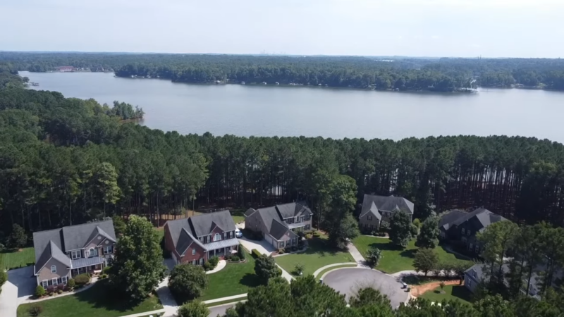 Aerial View of A Residential Neighborhood with Large Homes and Lush Greenery, Located Beside a Lake in Charlotte