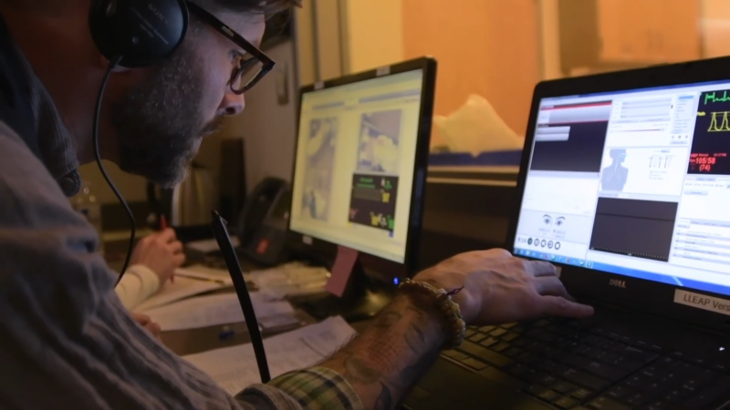 A Focused Man Wearing Headphones Works on Multiple Computer Screens Displaying Data and Graphs, Indicating an In-Depth Analysis of Educational Attainment and Workforce Composition in Alaska