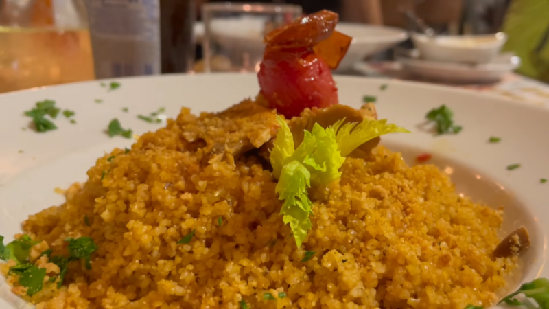 A Plate of Couscous with Vegetables and A Roasted Tomato on Top, Served in A Restaurant Setting