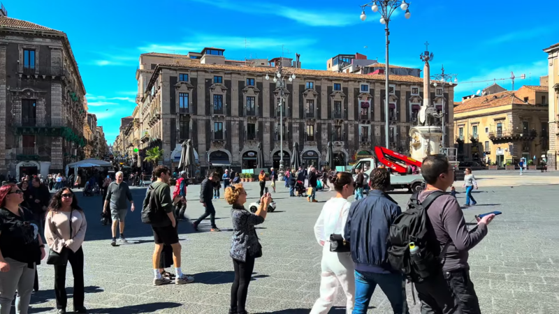 A Vibrant Scene of Tourists and Locals in A Bustling Square in Sicily, Showcasing the Diverse Architecture and Lively Street Atmosphere