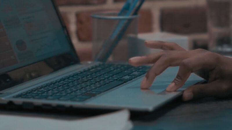 A Close-Up of A Person's Hand Using a Laptop, Possibly Representing the Shift Towards Remote Work and Digital Job Market Trends in New York City