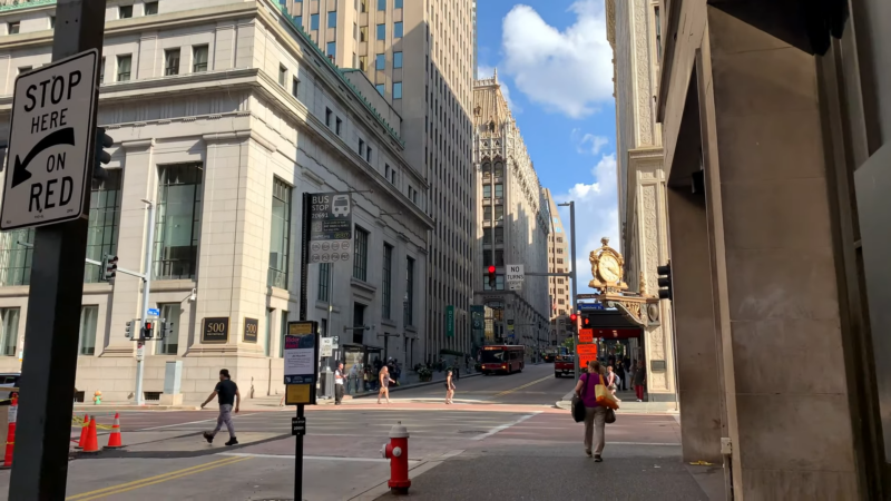 A Bustling Street Scene in Downtown Pittsburgh Showcasing Diverse Architecture and Busy Pedestrian Traffic Under Clear Skies