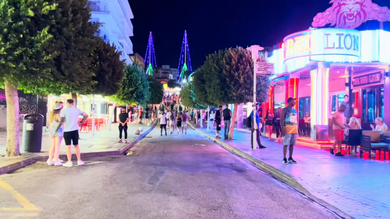 A Lively Street in Magaluf at Night with Neon Lights and People Walking, Hinting at Potential Increased Pickpocketing Activity in Crowded Areas