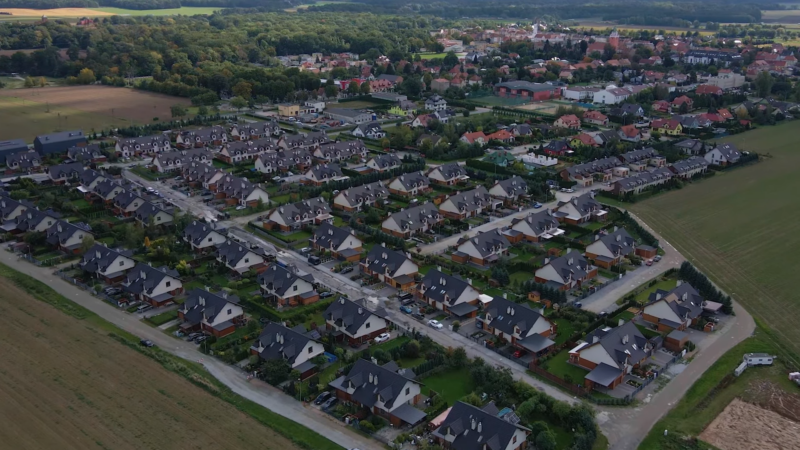 Aerial View of A Suburban Residential Area Surrounded by Open Fields and Forests, Highlighting Urban Development and Land Use Challenges