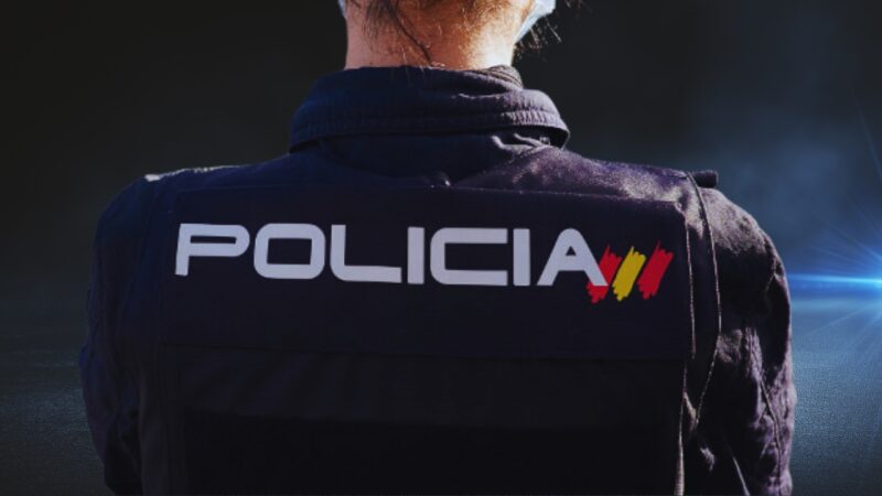 Back View of A Police Officer Wearing a Uniform Labeled 'Policia' with The Flag of Spain in Valencia