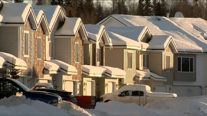 Row of Residential Houses with Steeply Pitched Roofs Covered in Snow, Reflecting the Living Conditions for Renters and Homeowners in Alaska