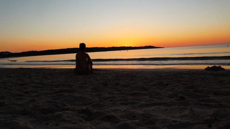 A Person Sits Alone on A Beach at Sunset in Mallorca, Suggesting a Peaceful and Safe Atmosphere for Walking Alone