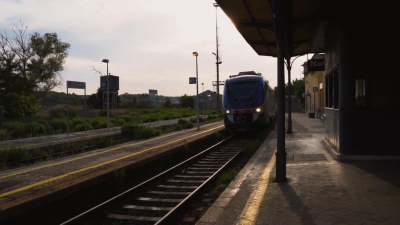 The Image Shows a Train Arriving at A Station in Sicily During the Evening, Highlighting a Mode of Economical Travel in The Region