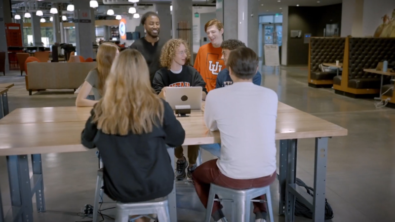 A Group of University Students Engaged in Discussion Around a Table in A Modern Campus Setting, Symbolizing Utah's Focus on Higher Education and Academic Achievement