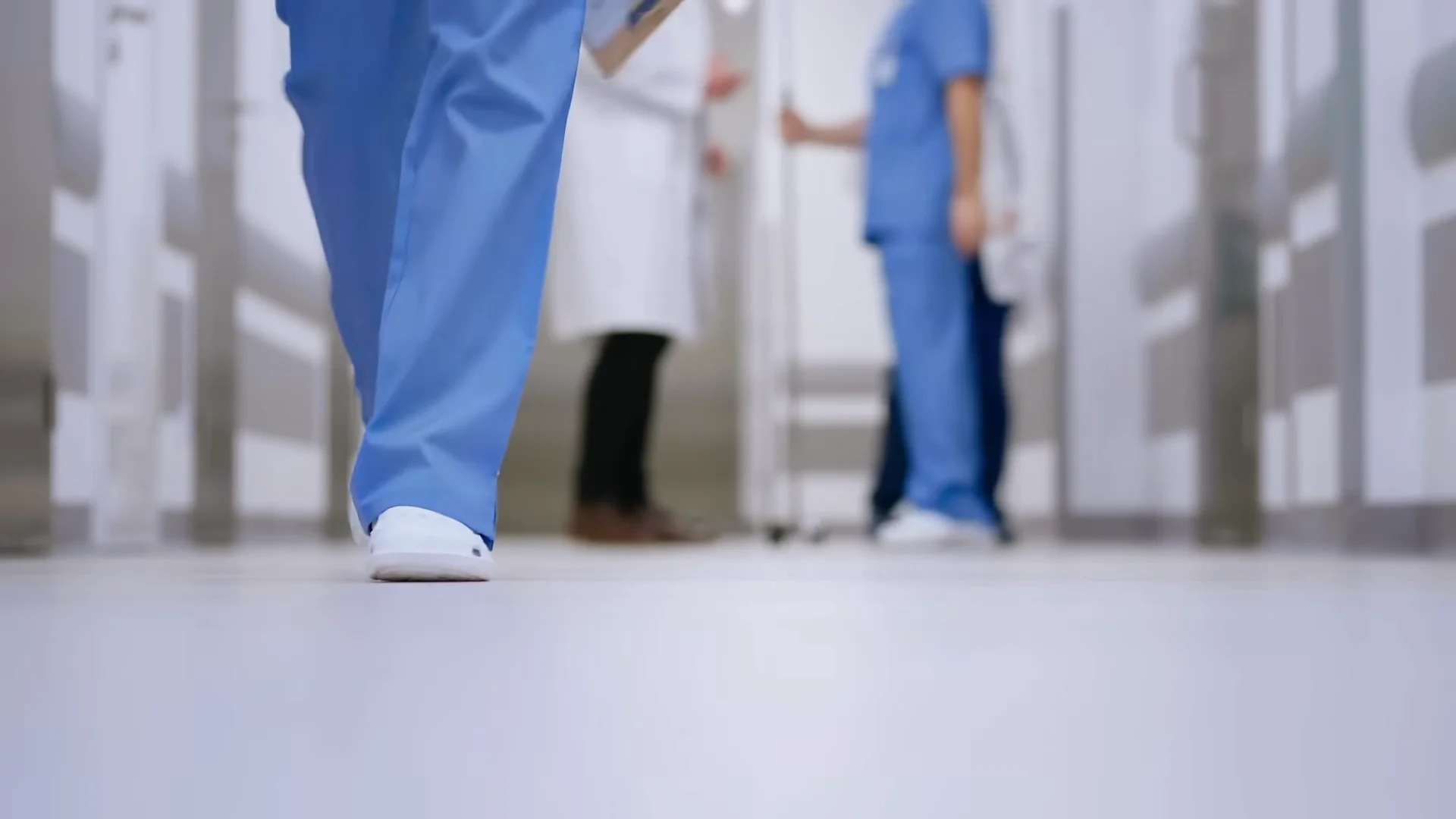 A Healthcare Worker in Blue Scrubs Walks Down a Hospital Hallway, Representing ER Visits in The U.S.