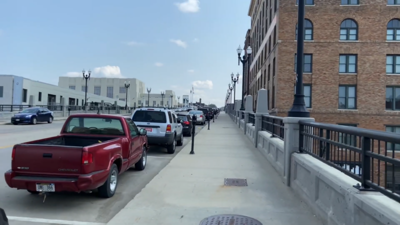 Street View of A Bridge in Omaha, Lined with Parked Cars and Multi-Story Buildings