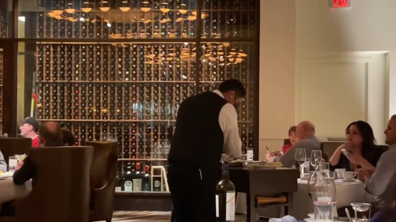 A Waiter Serves Guests in The Elegant Dining Area of Delmonico Steakhouse in Las Vegas