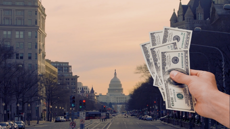 A Hand Holding Several Hundred-Dollar Bills in Front of The Washington D.C. Skyline