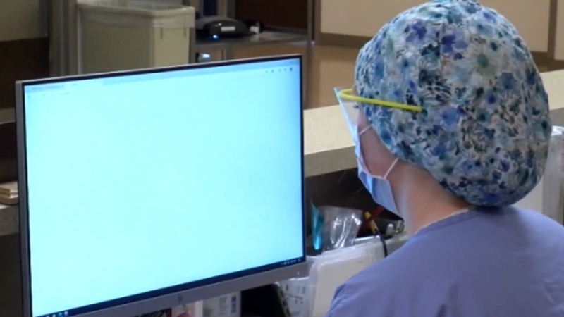 A Healthcare Worker Wearing a Mask Uses a Computer in A Minnesota Hospital