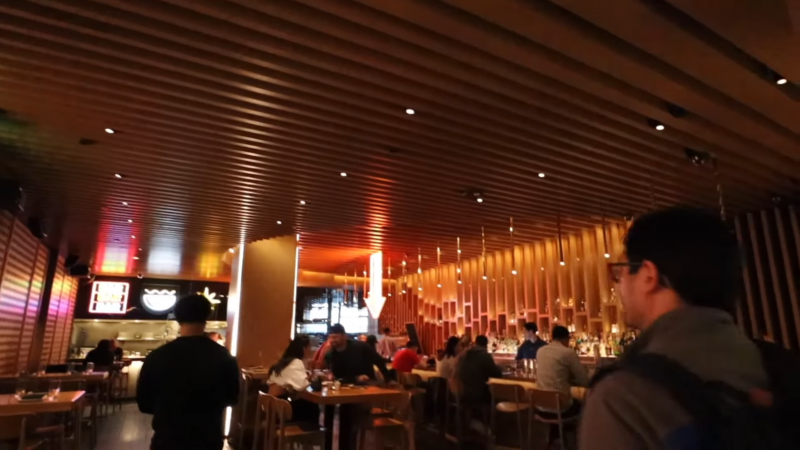  a Stylish, Modern Restaurant Interior at Momofuku Las Vegas, Featuring Warm Lighting, Wooden Decor, and Patrons Seated at Tables and A Bar