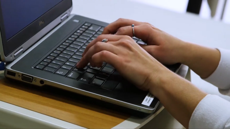 A Person Typing on A Laptop, Possibly Engaging in An Online Doctor of Nursing Practice (DNP) Program