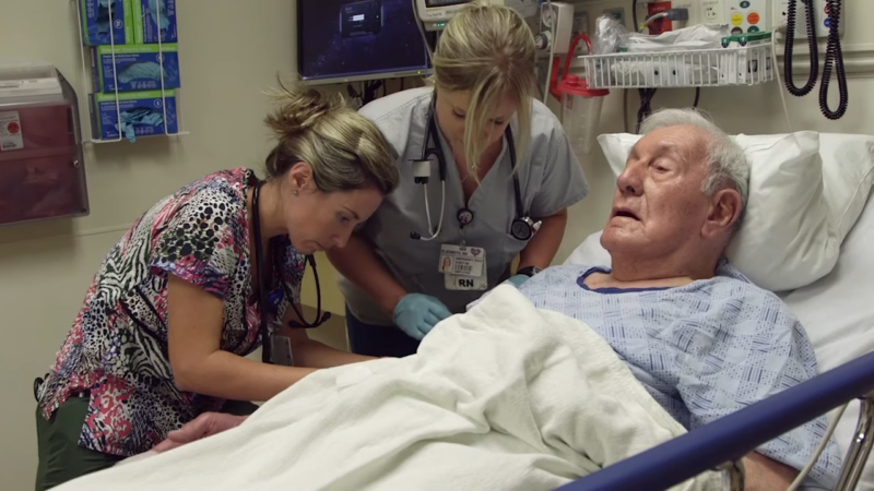 Two Nurses Attending to An Elderly Male Patient in A Hospital Bed