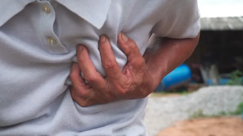 Person Clutching Their Chest in Pain, Showing One of The Early Symptoms of Heart Attacks