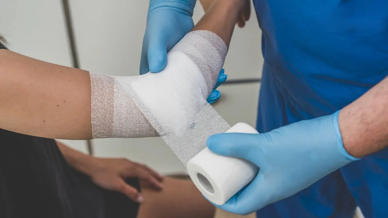 A medical professional wraps a bandage around a patient's arm