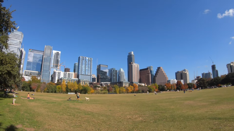 Auditorium Shores in Austin, Texas, with People Relaxing on The Grass and The City Skyline Behind