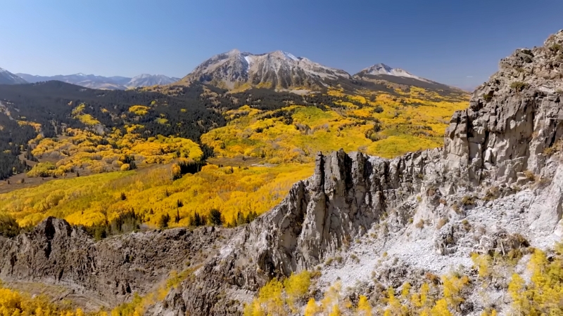 Cliffs and Golden Aspen Trees with Colorado's Rocky Mountains in The Background