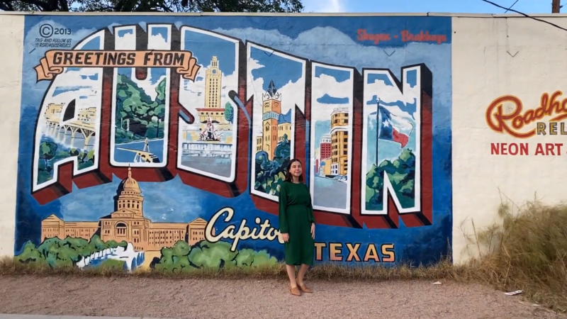 The “Greetings from Austin” Mural on First Street, with A Person Posing in Front