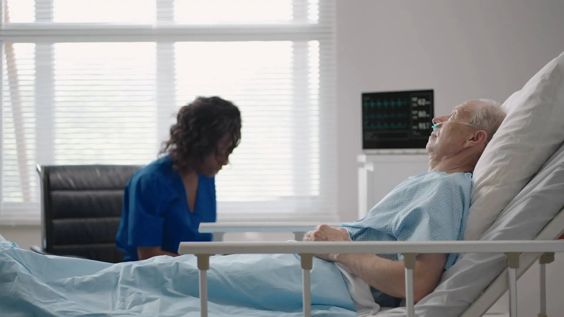 Elderly patient in a hospital bed with an oxygen tube