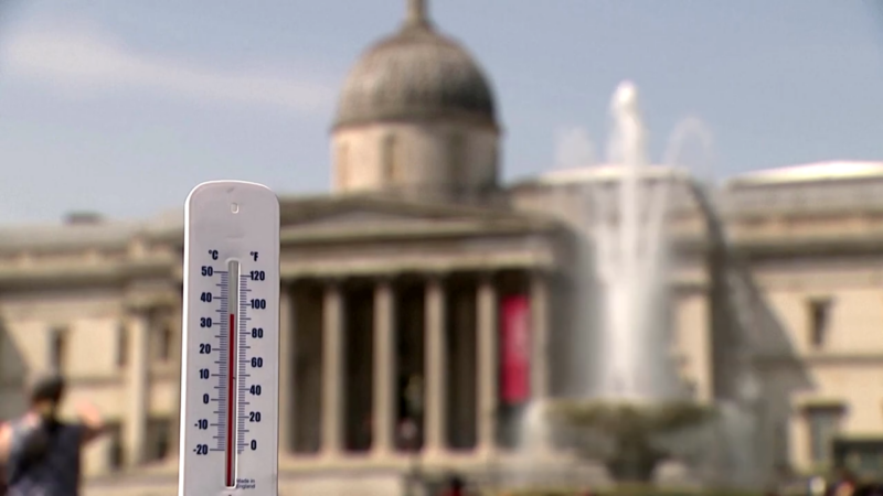 Thermometer Displaying High Temperatures in Front of A Historical Building with A Fountain in The Background