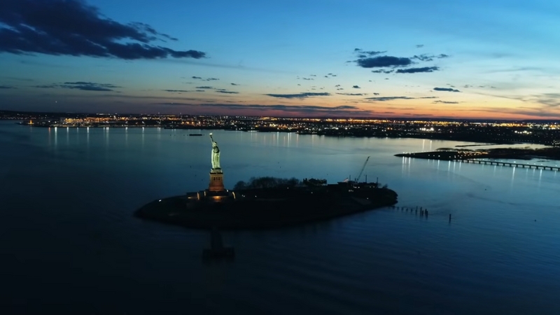 Aerial View of The Statue of Liberty at Sunset with The New York Skyline in The Background