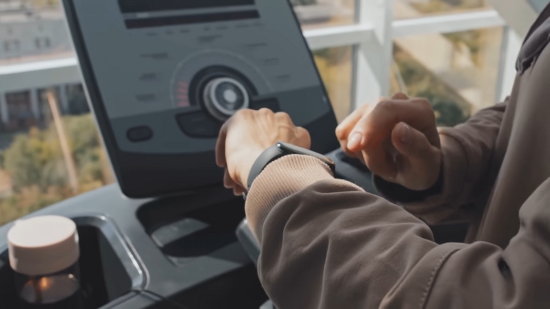 Person Interacting with A Smartwatch and Health Monitoring System on A Digital Screen