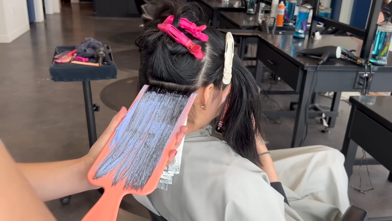 A Person Having Their Hair Dyed in A Salon, with The Dye Applied to The Roots