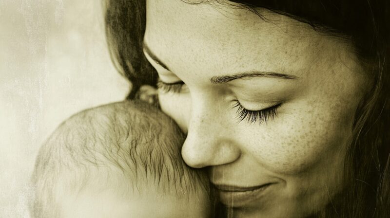 Sepia-toned image of a mother gently holding her baby close to her face with her eyes closed.