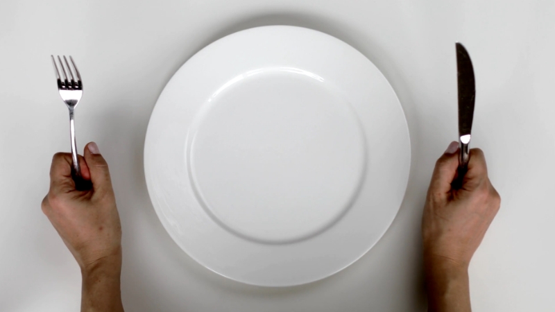 A fork and knife placed on an empty plate, symbolizing child food insecurity in some counties