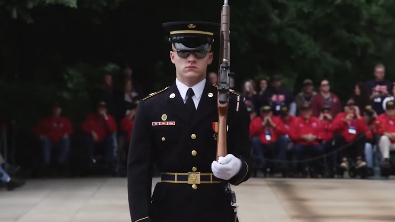 A member of the U.S. military in ceremonial uniform standing guard with a rifle