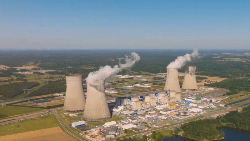 Aerial view of a nuclear power plant with cooling towers releasing steam