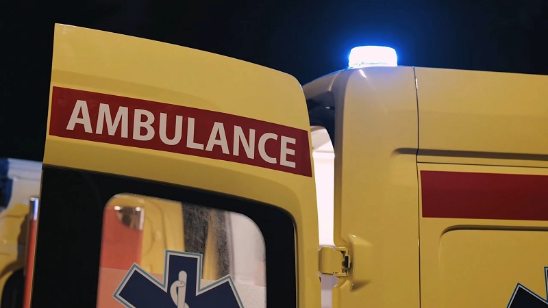 Rear view of an ambulance with its doors open and emergency lights flashing at night
