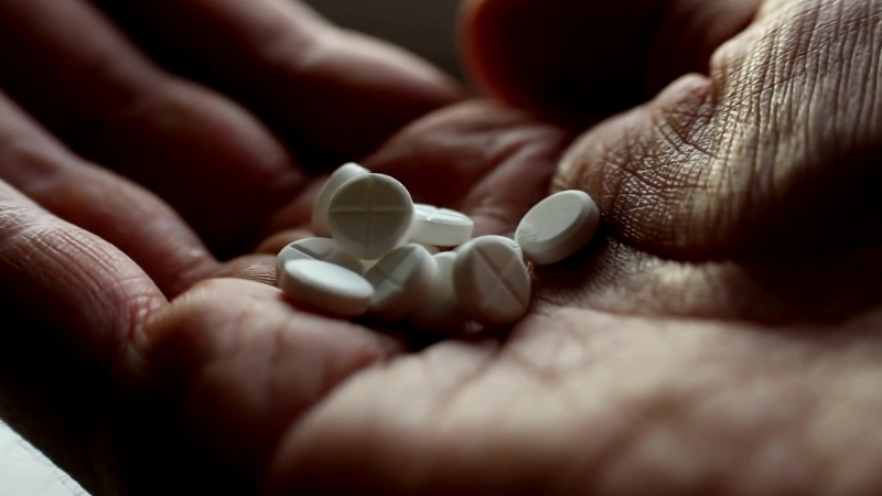 A hand holding several white pills, symbolizing the ongoing issue of drug overdoses in Florida