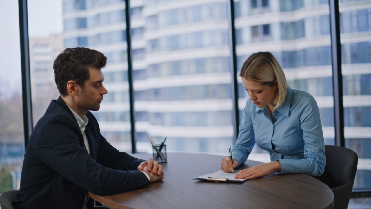 An employer takes notes in a job interview at a modern office