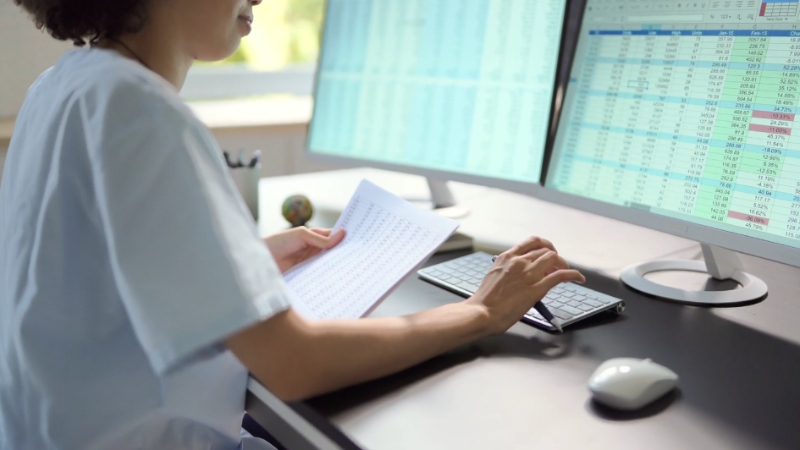 A medical professional reviews data on multiple monitors, highlighting the role of digital tools in medical billing