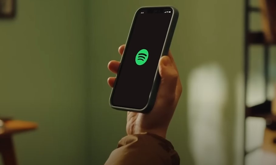 A person holds a phone with Spotify app opened
