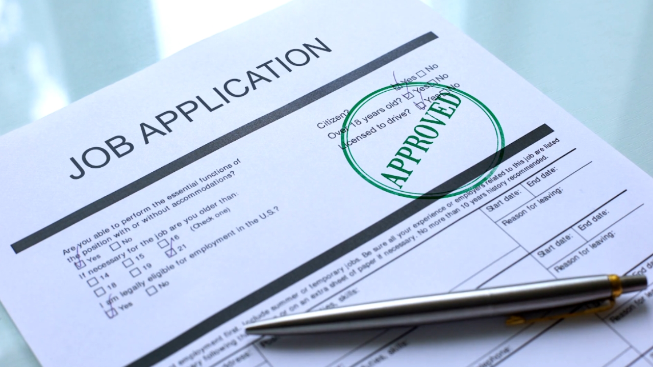 A job application form has an approved stamp beside a pen
