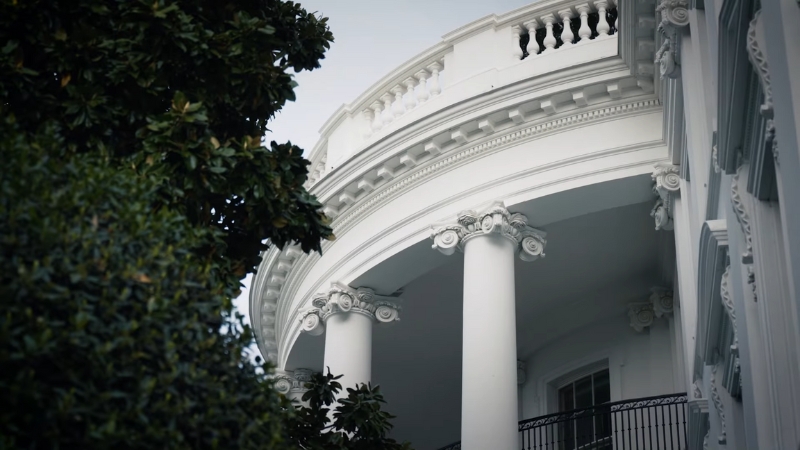 A close-up of the White House balcony with decorative columns and greenery