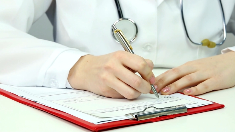 A doctor completing a form, reflecting steps to address impulse control disorders