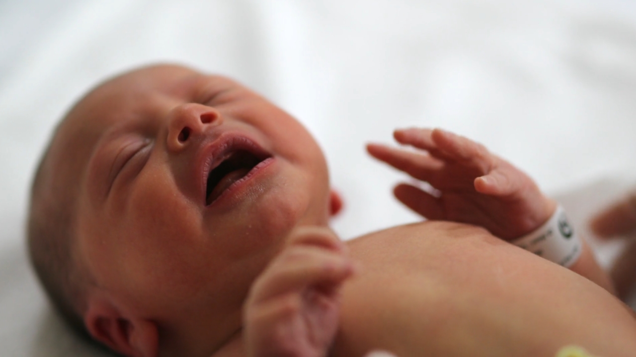 A newborn baby cries on a hospital bed